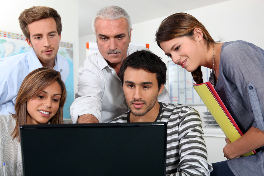 Colleagues reviewing information together at a laptop during a workplace discussion